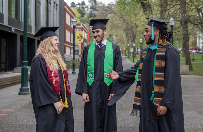 Graduating students in regalia walk the Park Blocks
