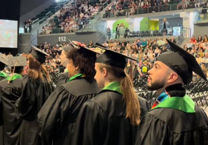 Graduates in regalia process to stage