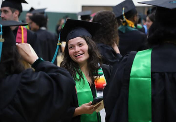 A graduate smiles brightly while chatting before the College of Urban & Public Affairs ceremony