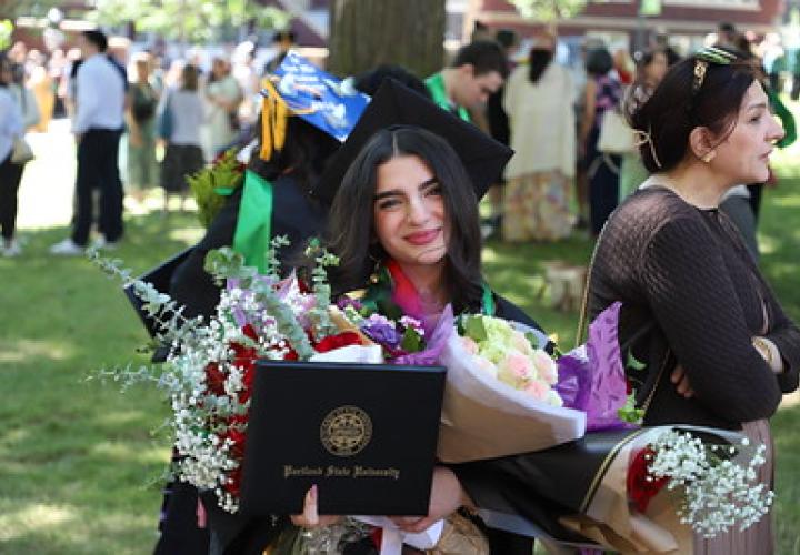 College of Liberal Arts and Sciences graduate holding flowers and diploma after commencement