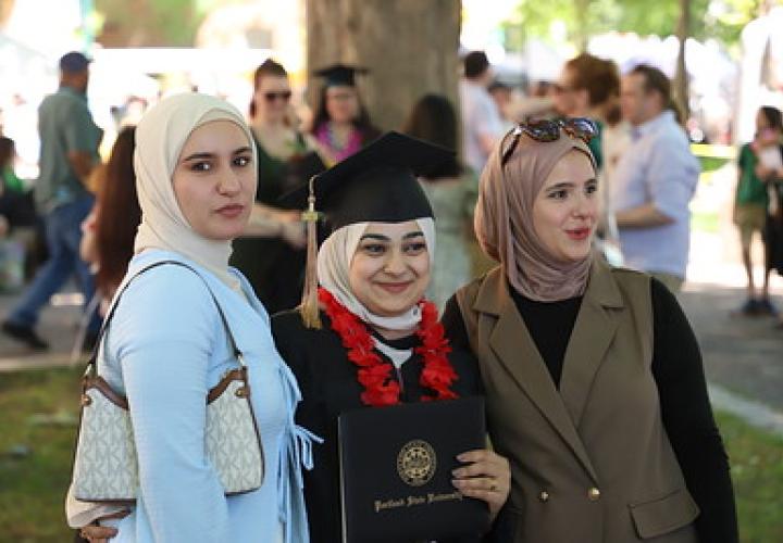 Three graduates and guests pose together outdoors during PSU commencement celebrations