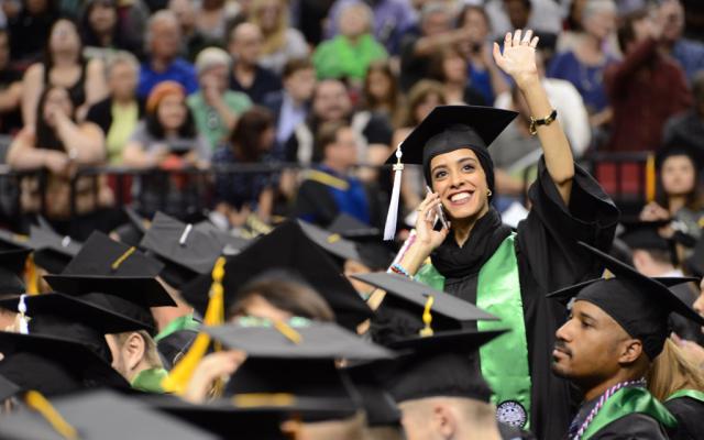 Student waiving to family at commencement