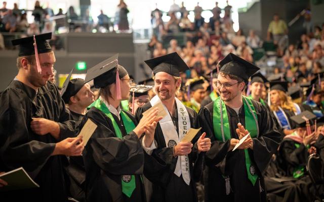 Graduates clapping at commencement ceremony