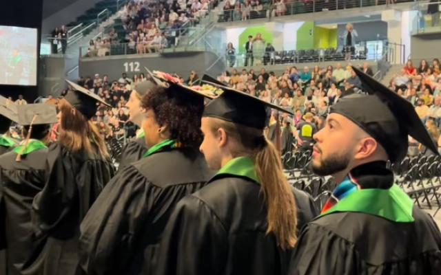 Graduates in regalia process to stage