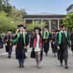 Graduates in caps and gowns walk on campus