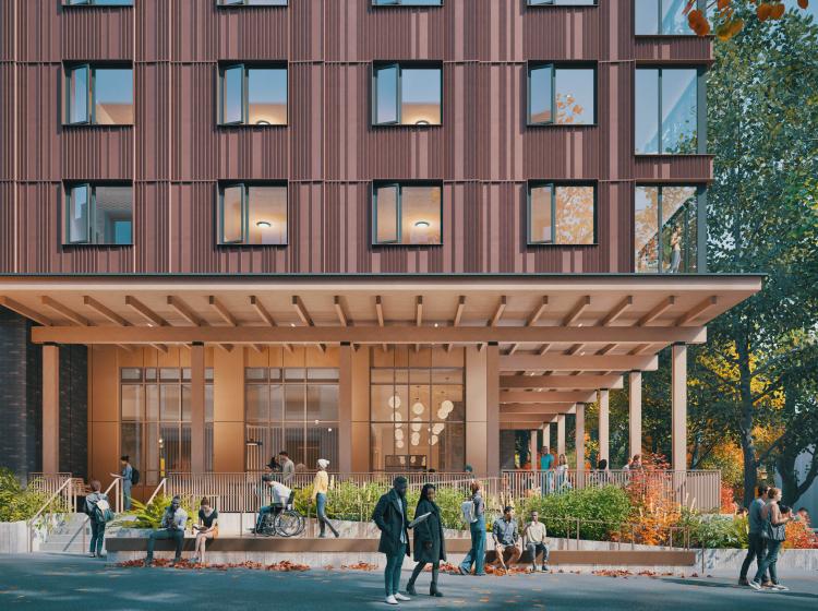 picture of psu new housing building. brown building with many people standing in front with fall foliage