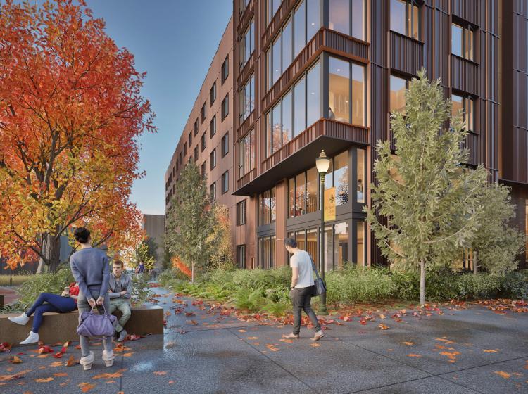 picture of psu new housing building. brown building with many people standing in front with fall foliage