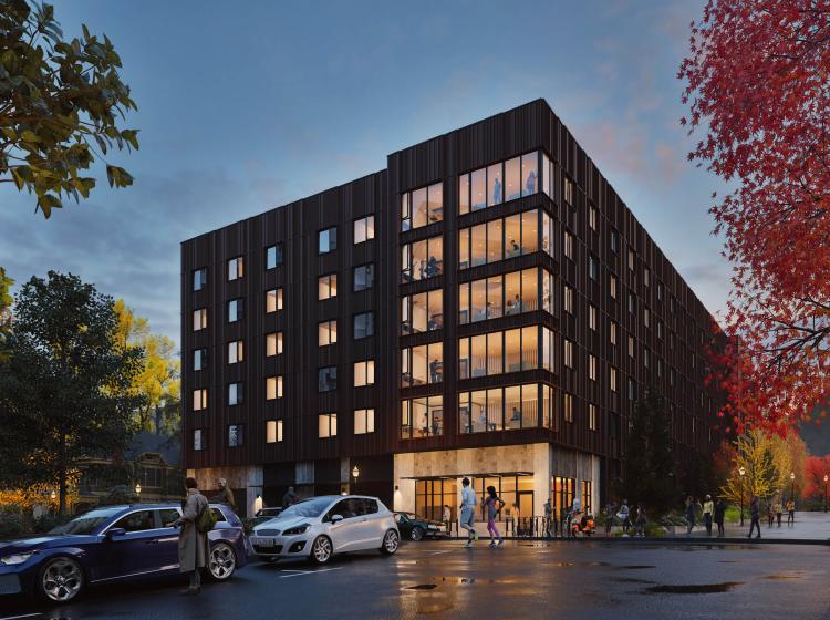 picture of psu new housing building. brown building with many people standing in front with fall foliage