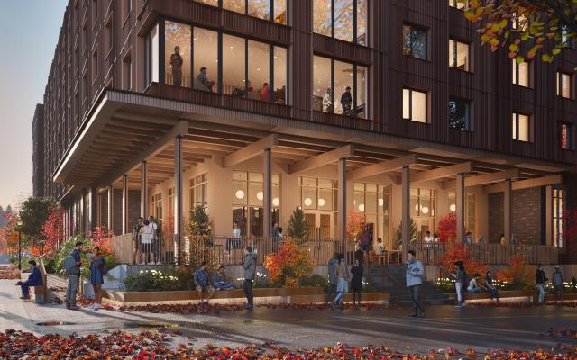 picture of psu new housing building. brown building with many people standing in front with fall foliage