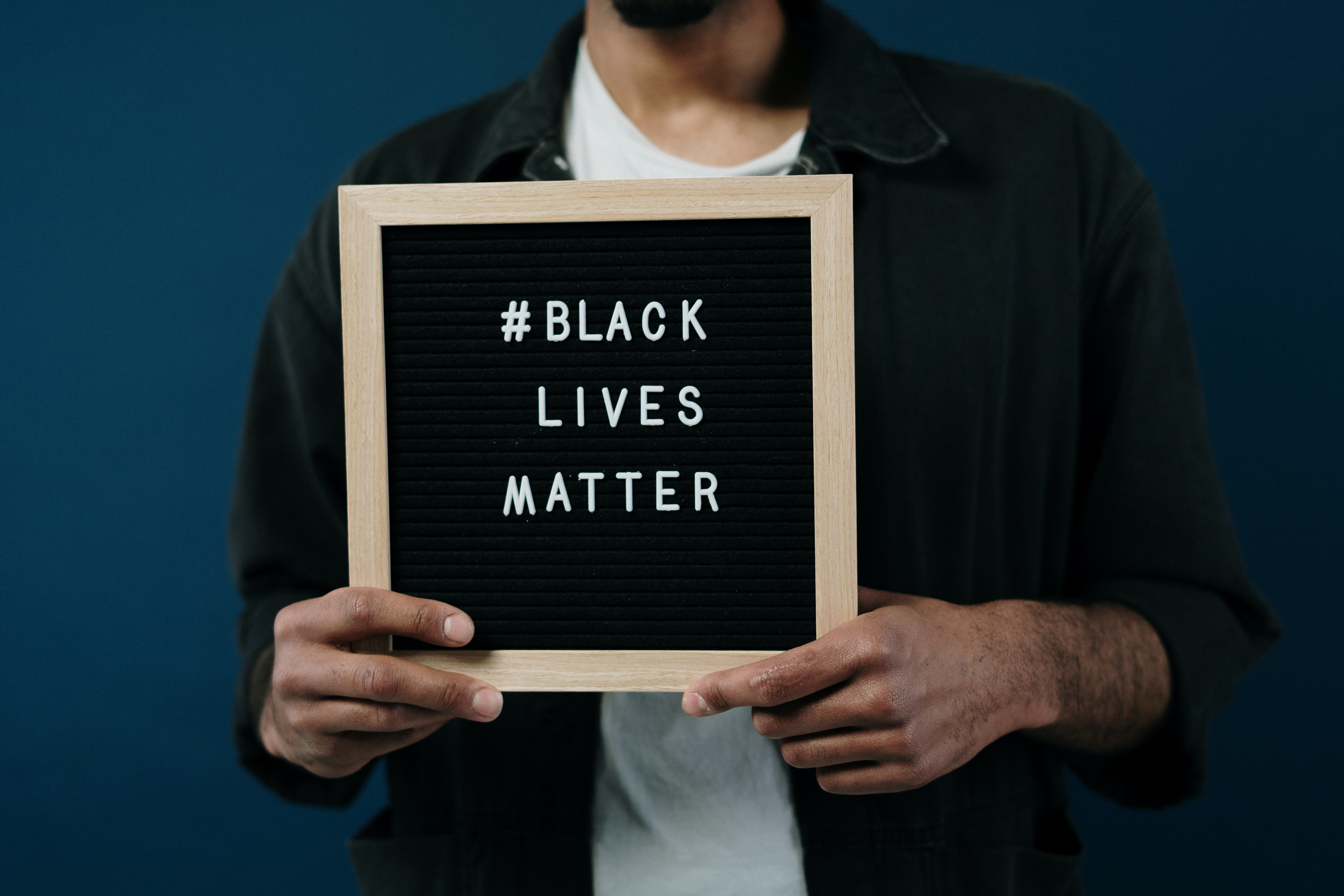 A man holding a pin board with "#Black Lives Matter" written on it