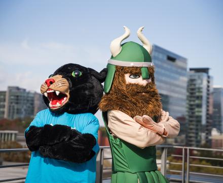 PCC panther mascot and PSU victor viking mascot stand back to back