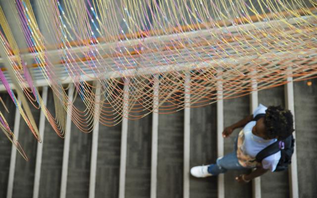 Art installation hanging over student walking down stairs