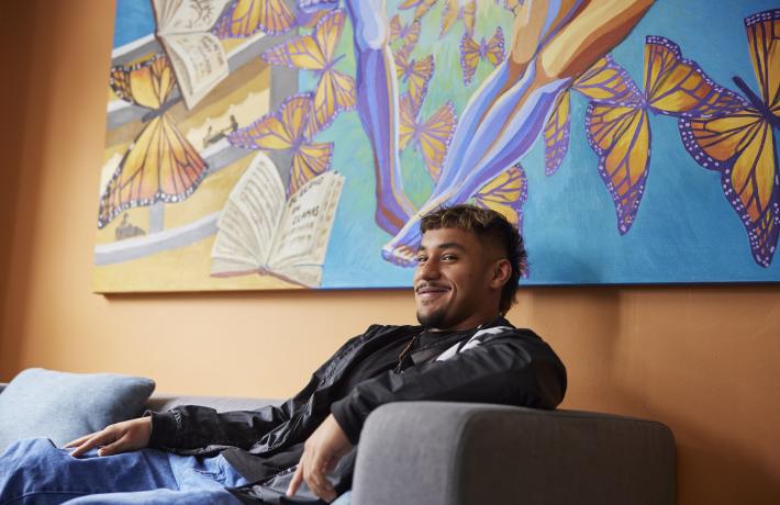 Student on couch; backdrop is mural with butterflies