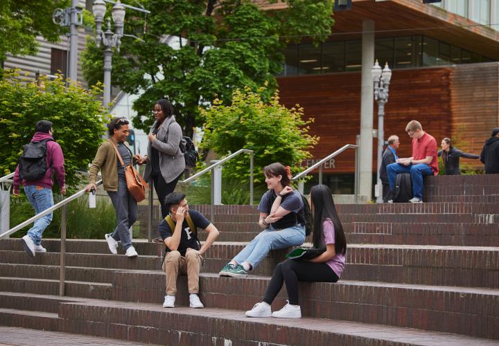 Groups of students sitting or standing on steps of Urban Plaza