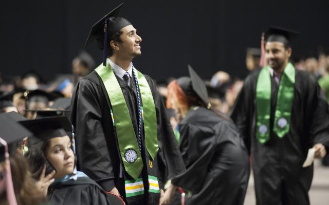 Student in cap and gown at Commencement looking into stands