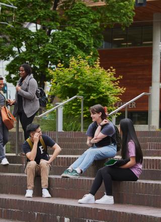 Groups of students sitting or standing on steps of Urban Plaza