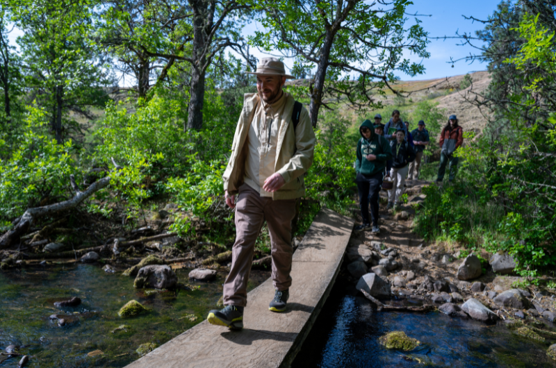 Student walking on footbridge across stream