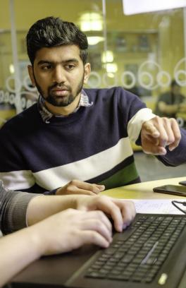 Two Portland State students working on a laptop at a table.