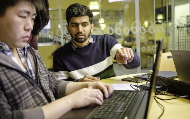 Two Portland State students working on a laptop at a table.