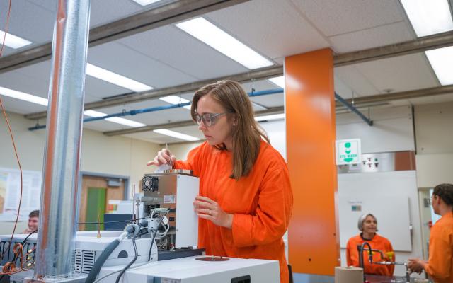 Researcher in orange lab coat working with sample