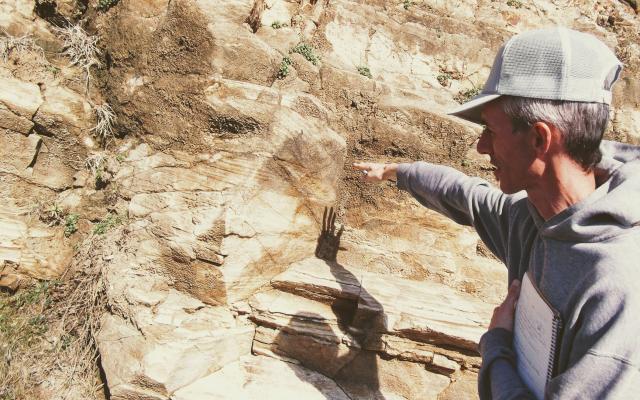 Researcher pointing to rock