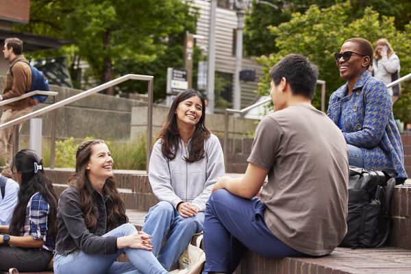 Four students sitting on the Urban Plaza steps