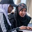 Two female students sitting and looking at a laptop .