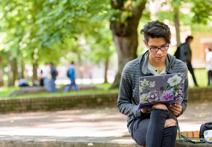 Student sitting in Park Blocks with laptop. 