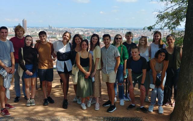 students posing together with cityscape behind them