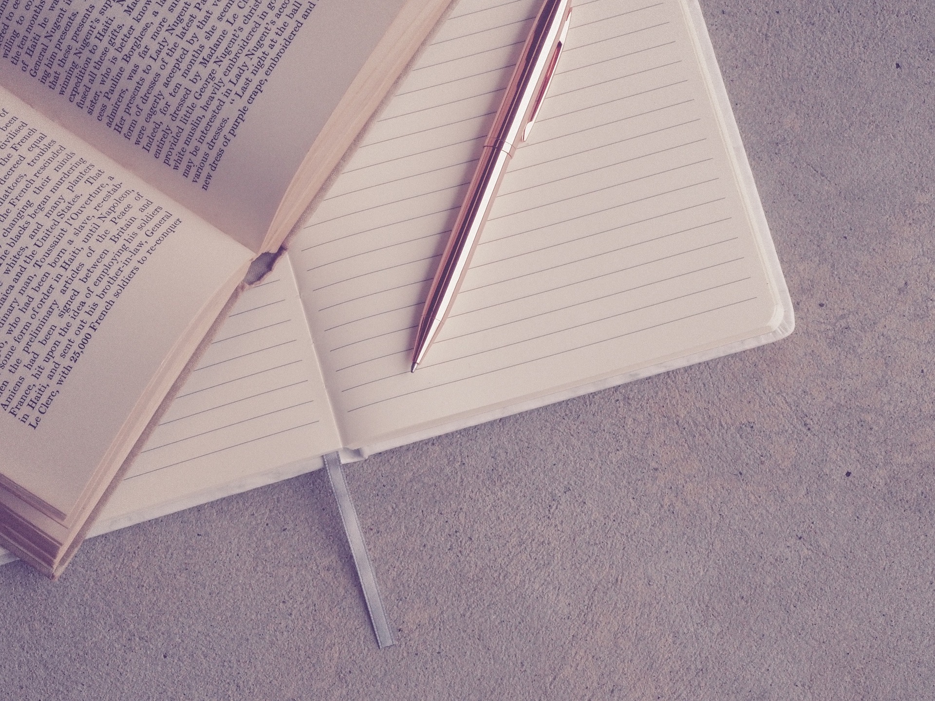 Open book, notebook, and pen signifying professional learning.