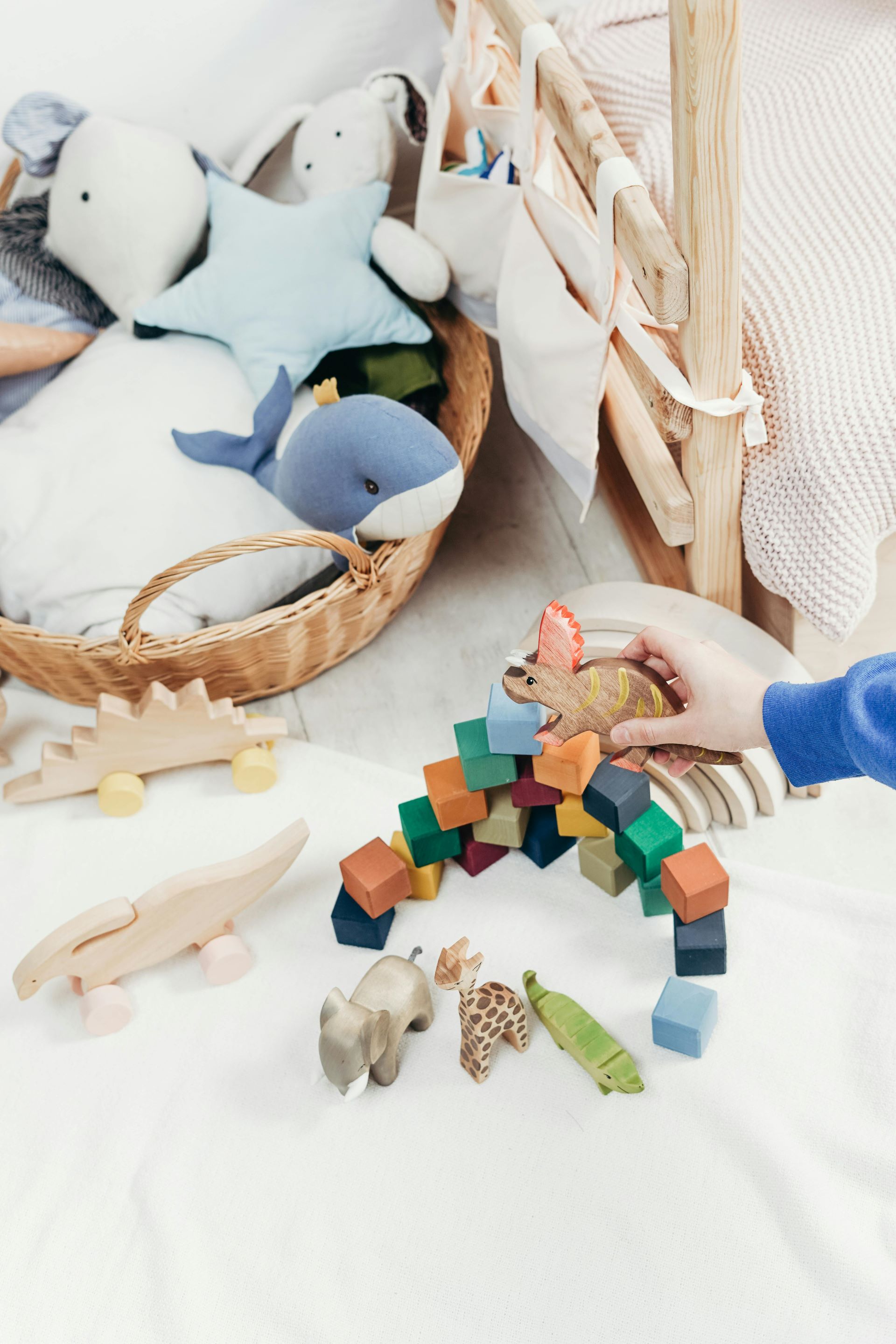 A child with a dinosoar in their hand playing with their toys.