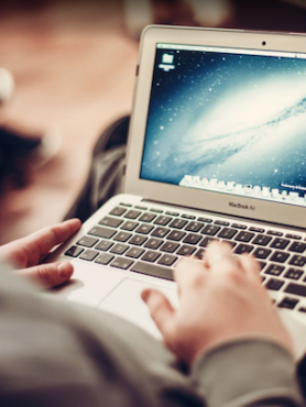 Individual typing on a laptop.