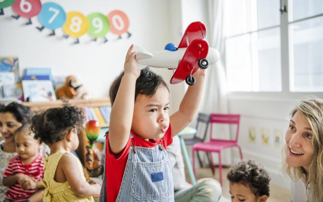 Child at daycare holding an airplane