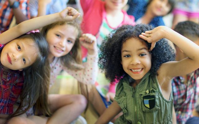 A group of children sitting together and smiling at the camera.