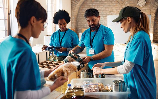 A group of community volunteers work together to prepare food boxes.
