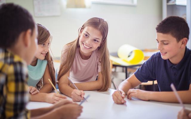 A group of middle school students chat together between assignments.