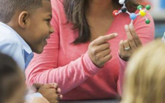 Science teacher showing students a model of atoms