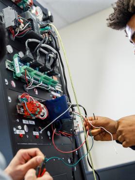Students plugging wires into a computer