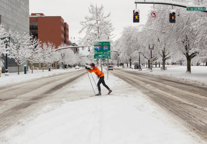 Person cross country skiing across street in downtown Portland during a winter storm. 