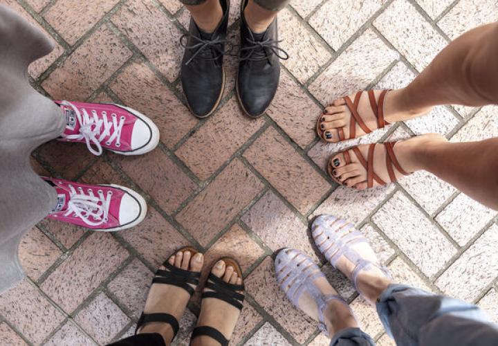 Photo looking down at circle of five students' feet. 