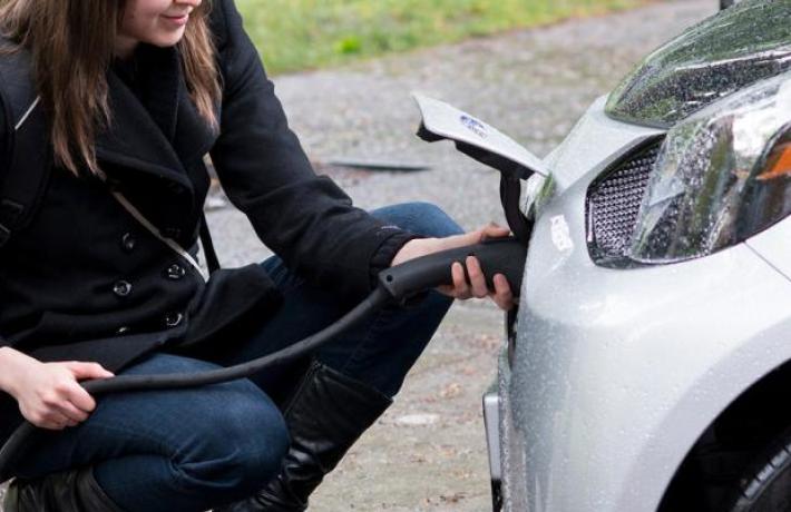 Portland State University sustainability program student charging an electric car