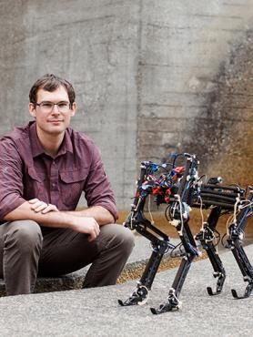 Alex hunt poses with two robots