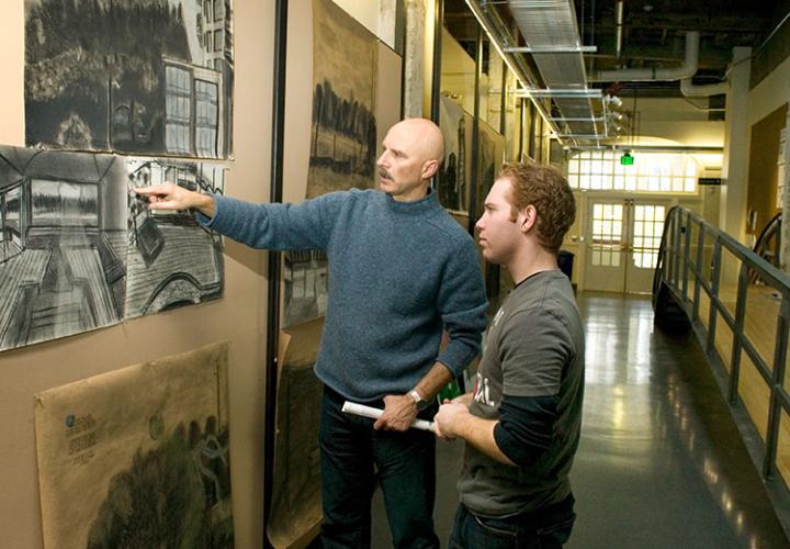 Two men inspect a photo hanging on the wall