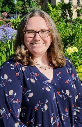 a woman with brown hair smiles against a background of plants