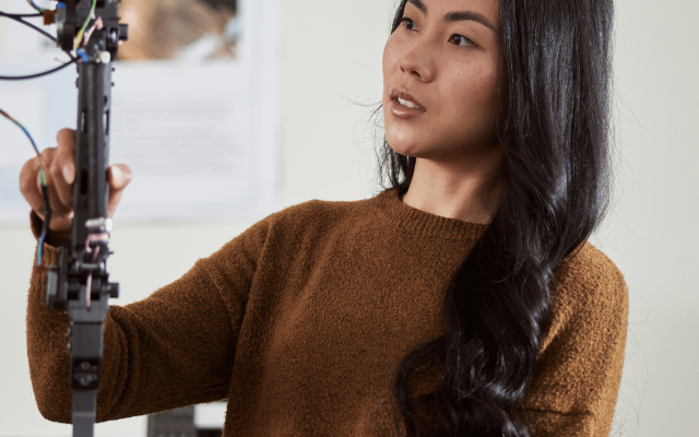 A woman adjusts a robotic limb. 
