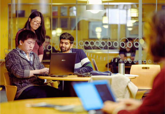 A group of students work together on a laptop. 