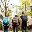 Back of three students wearing backpacks walking away