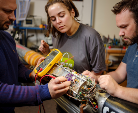 Three people work on an electrical project.