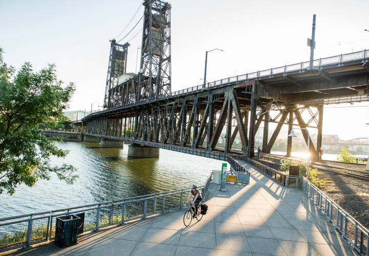 Person riding bike underneath bridge in Portland