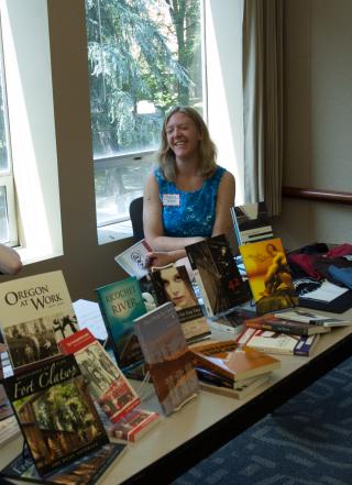 Two people sitting at an Ooligan Press booth, selling books.